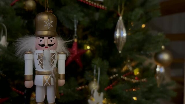 Nutcracker soldier on a Christmas tree. Seasonal toy figure before an illuminated artificial Christmas tree with lights and colorful decorations