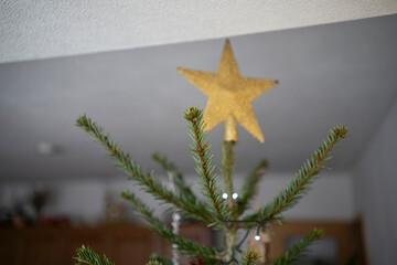 Blurred golden star on top of Christmas tree with soft selective focus, festive symbol and holiday spirit