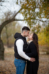 Fototapeta premium A young man and woman hugging sweetly in an autumn park