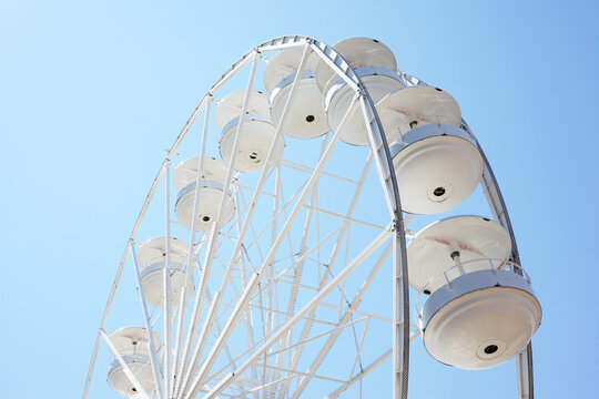 White Ferris Wheel Against Clear Blue Sky, Minimal Amusement Park Concept - Powered by Adobe