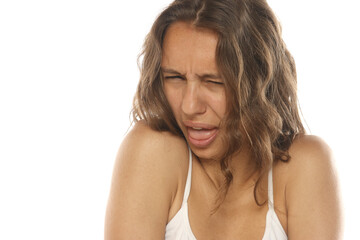 Fototapeta premium Studio shot of a young woman with long brown hair and no makeup, disgusted expression with tongue out, portrait, on a white background