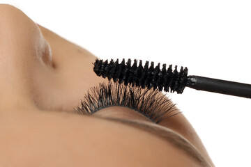 Studio shot close-up of a woman applying mascara to artificial eyelashes on a white background