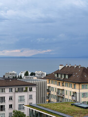 Overcast View of a European City by a Lake with Distant Mountains