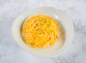 Scrambled eggs with herbs on a white plate on marble table