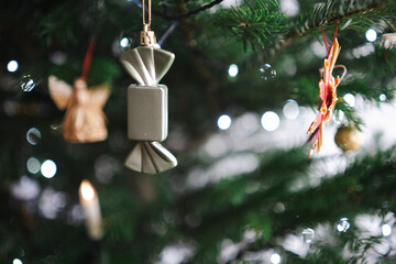 Toy candy and festive ornaments on Christmas tree with soft selective focus, greeting card concept