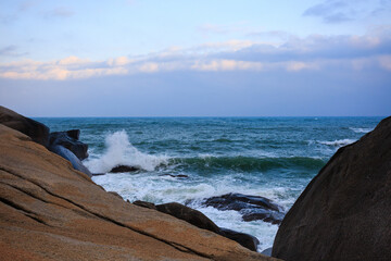 The scenery of Stone Park in Hainan, China, features emerald-green seawater crashing against the rocks, creating beautiful waves.