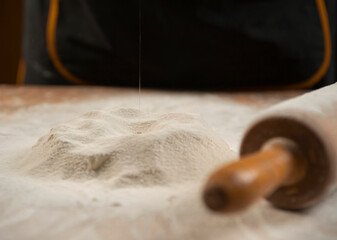 Close-up of a rolling pin and piles of flour with yolk on it