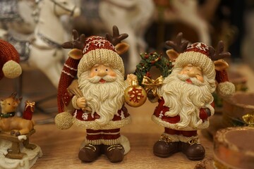 lucky vintage Santa Claus figurines in red fur coats with Christmas trees and holiday wreaths on the table close-up as a gift and decoration of winter interiors