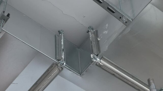 Construction worker installing metal frame for drywall ceiling using cordless drill. Professional interior renovation process, ceiling mounting system, metal profiles installation, home improvement, b