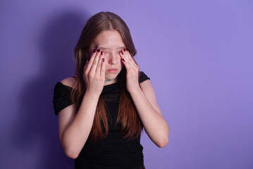 A young girl student has been preparing for a college exam all night and hasn't had enough sleep, feels tired, covers her eyes with hands, not ready for the exam