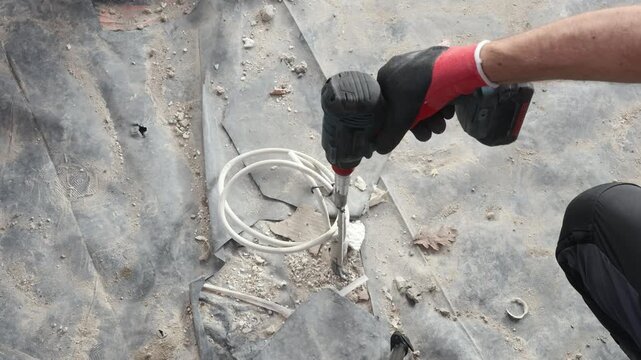 Construction worker drilling and removing floor material with power tools during renovation. Home improvement, repair work, demolition and building process concept