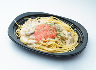 Delicious spaghetti with creamy sauce and tomato topping on black plate