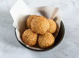 Delicious sesame balls in a black bowl on marble countertop