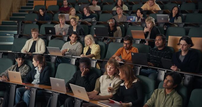 Diverse Group of College Students Sit in a University Lecture Hall, Listening, Typing on Laptops, and Writing Notes, Academic Class on Higher Education, Study Skills, Exam Preparation. - Powered by Adobe