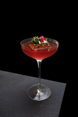 A sophisticated cocktail with ice cube decorated with greens, in a stylish glass 