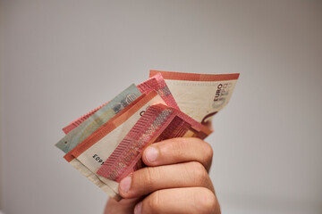 Close-up of euro banknotes held in hands.