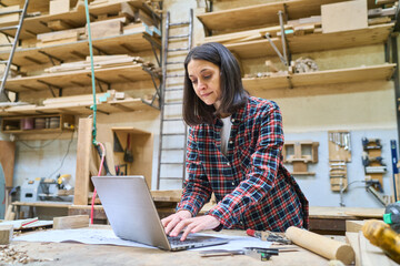 Female carpenter using a laptop in a wood workshop