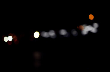 Defocused city lights forming scattered circular spots on dark background. Blurred points vary in