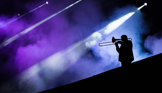 Silhouette of Trombone Player on Stage with Purple Spotlights and Smoke