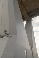 A low-angle perspective highlights a large, angular concrete support column of the Bhumibol Bridge (Industrial Ring Road Bridge), The imposing height and geometric forms of the bridge with sharp lines
