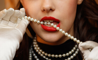 A woman is wearing a pearl necklace and white gloves