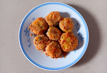 Top view of Indonesian potato fritters also known as perkedel on a white plate isolated on marble table.