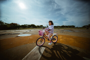 Fototapeta premium A happy girl is enjoying riding a colorful bicycle on a beautiful sunny day