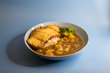 Japanese chicken katsu curry with rice and vegetables on blue background