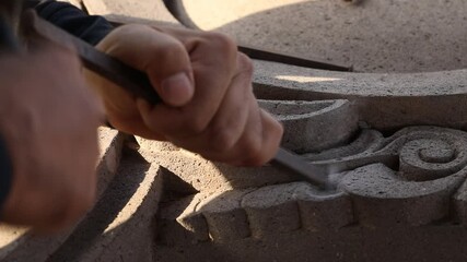 Close up of artisan hands carving stone with chisel and hammer. Skilled sculptor creating detailed architectural ornament. Traditional manual craftsmanship process in a workshop setting.

 - Powered by Adobe