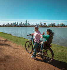 Obraz premium Mother And Child HighFiving By Lake, Helmets And Smiles, Joyful Bond Captured During Short Stop
