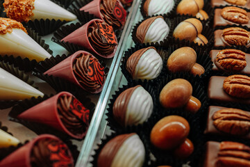 Lots of handmade chocolate candies with nuts on the counter of a candy shop