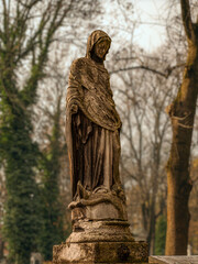 Weathered Hooded Statue in a Quiet Cemetery Garden at Dusk, Solitude and Reverence