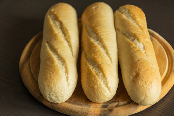 Three Small Bread Baguettes on Wooden Cutting Board