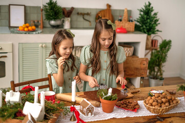 The girls are making gingerbread Christmas cookies by cutting out Christmas figures from the dough.