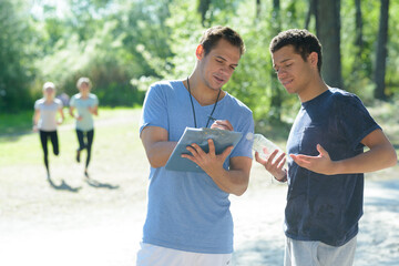 smiling man showing a training table to sportman