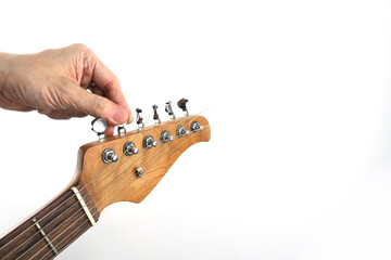 Close-up of a hand adjusting guitar tuning pegs on the headstock, showing guitar tuning process and string tension. Minimal studio shot isolated on white background, focusing on guitar maintenance, mu