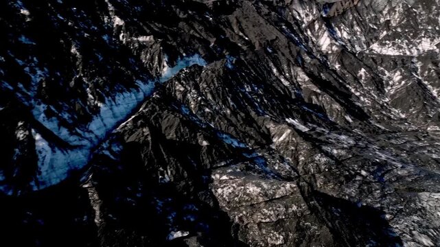 Cinematic aerial drone flight through Katla ice cave tunnel showing blue ice with black volcanic ash veins and green mossy mountains in Iceland 4K.