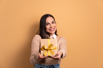 happy brazilian woman giving gift box in all beige colors. birthday, christmas, gift box concept.