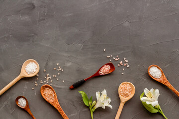 Fototapeta na wymiar Beauty spa therapy cosmetics and wellness flat lay - sea salt in many spoons with flowers, top view