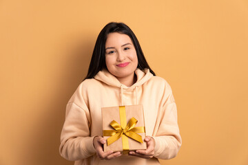 happy caucasian woman giving gift box in studio shot. christmas, happy birthday, celebration concept.