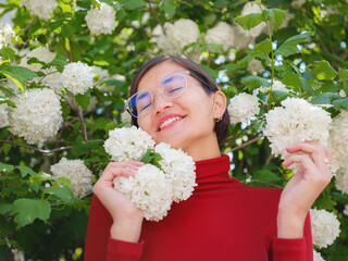 Woman in glasses and red turtleneck, dressed in business style, stands in center of Frankfurt, surrounded by modern buildings and urban life, embodying professionalism and confidence