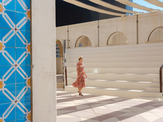 Young woman exploring Qasr Al Hosn Park in Abu Dhabi. Surrounded by lush greenery and historical landmarks, she enjoys the serene atmosphere and Emirati heritage in heart of city.