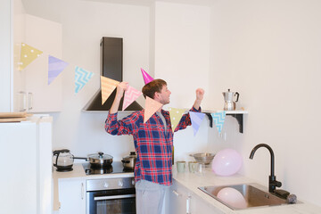 Young man celebrates his birthday at home, surrounded by a cozy and festive setting. He enjoys his special day , creating memories , preparing for the holiday, decorating the room