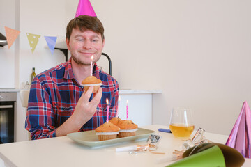 man celebrates with four cupcakes topped with candles in place of traditional birthday cake. Smiling and joyful, he enjoys cozy and unique celebration, creating warm and memorable festive moment.