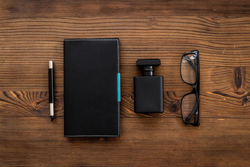 Male accessories flat lay with perfume notepad and glasses in black color