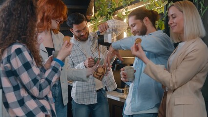 Group Caucasian friends eating cookies in office startup company smiling talking lunch break multiethnic business men women informal casual team colleagues relaxing indoors drinking coffee eat snacks