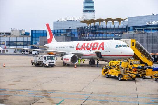 Vienna, Austria - 15 December, 2025: airplane from Lauda is parked at Vienna International Airport. Ground crew is loading luggage onto aircraft. The terminal building is visible in the background.
