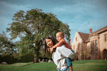 Fototapeta premium A heartwarming scene of a loving mother carrying her happy child outdoors, surrounded by stunning nature