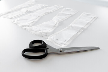 Scissors beside fabric corset pattern pieces on white table for tailoring  