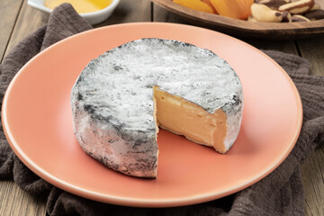 Ashes aged creamy cheese over wooden table